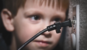 child looking a loose electric plug in wall